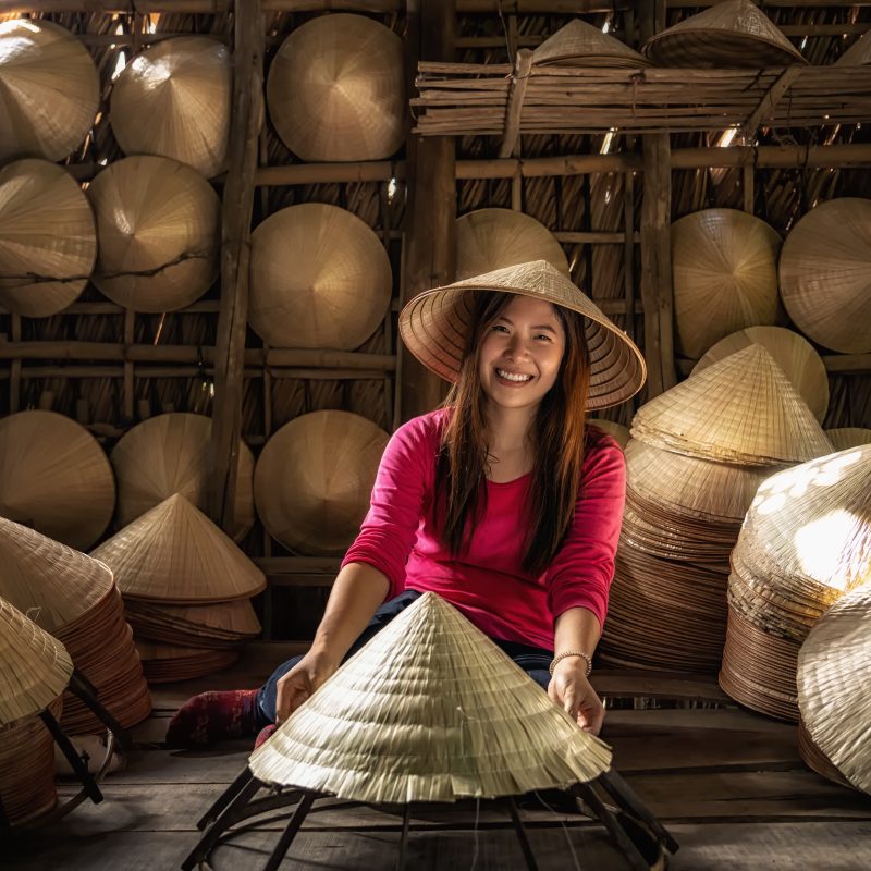 Asian traveler female craftsman making the traditional vietnam hat in the old traditional house